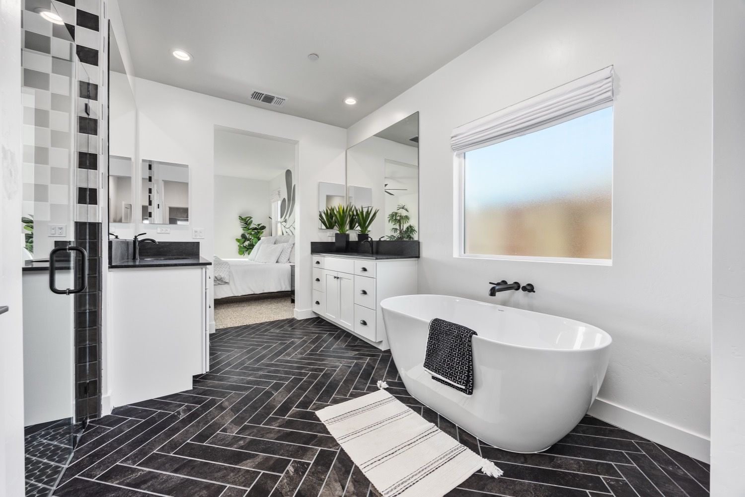 Modern white bathroom with a soaking tub and dark patterned floor.