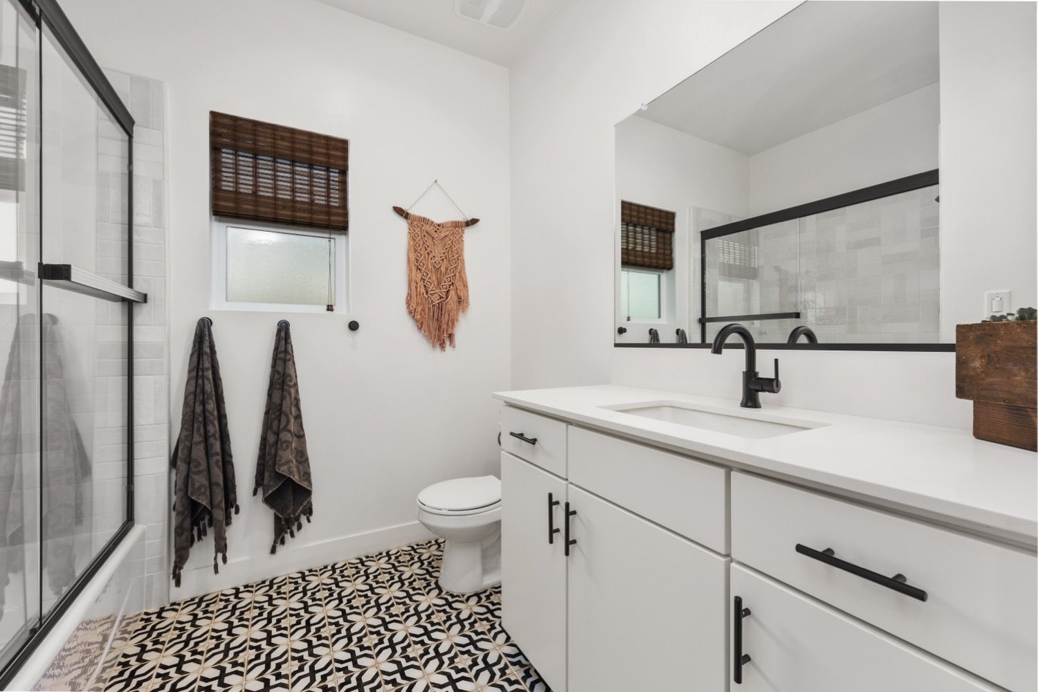 A white stucco house with a terracotta roof, blue door, and wooden garage doors, set on a green lawn.