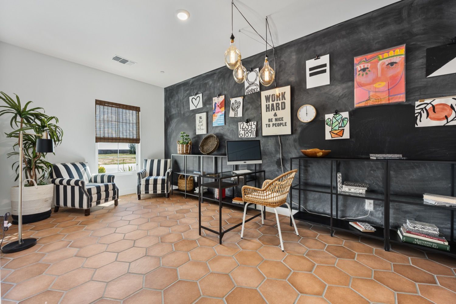 Stylish home office with hexagon tiles, black accent wall, shelves, art, and patterned furniture.