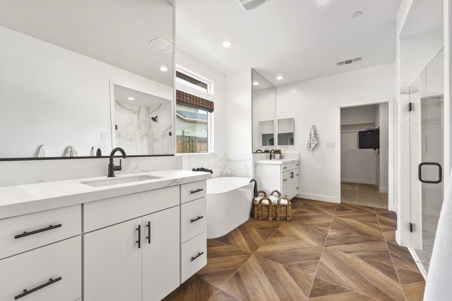 Modern white bathroom with wood-patterned floor, white cabinets, a bathtub, and a glass shower.