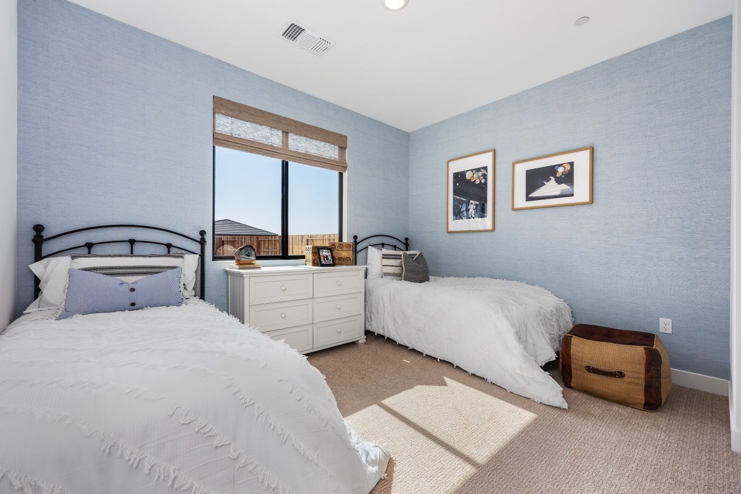 Bedroom with two twin beds, blue textured walls, and a window with a view.