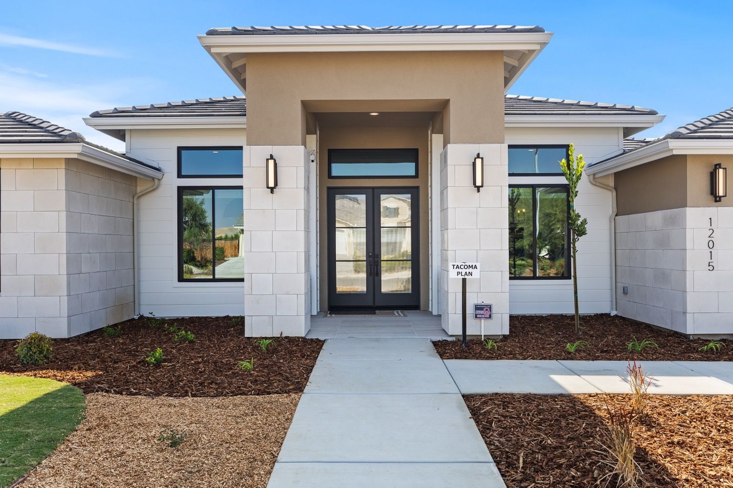Modern home exterior with white stone facade, front entrance with double doors, and walkway.