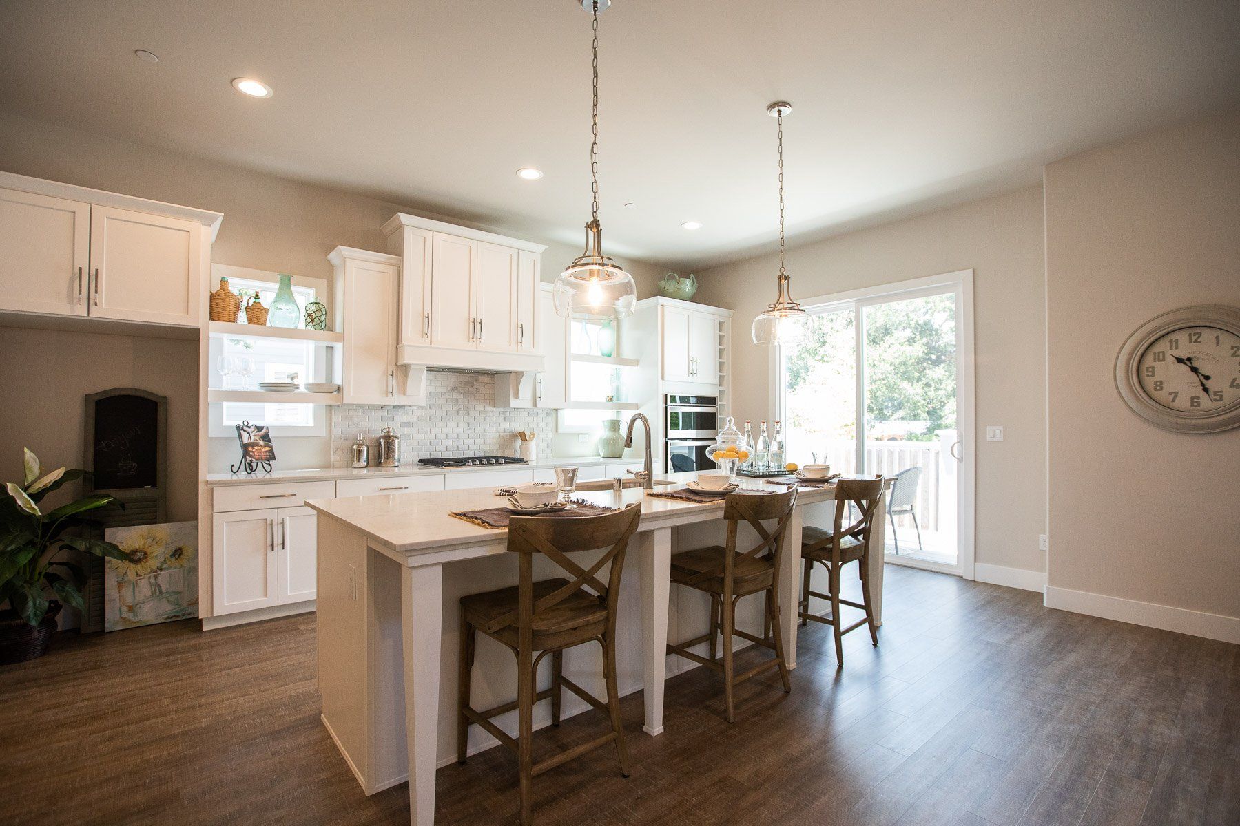 A kitchen with a large island and stools and a clock on the wall.