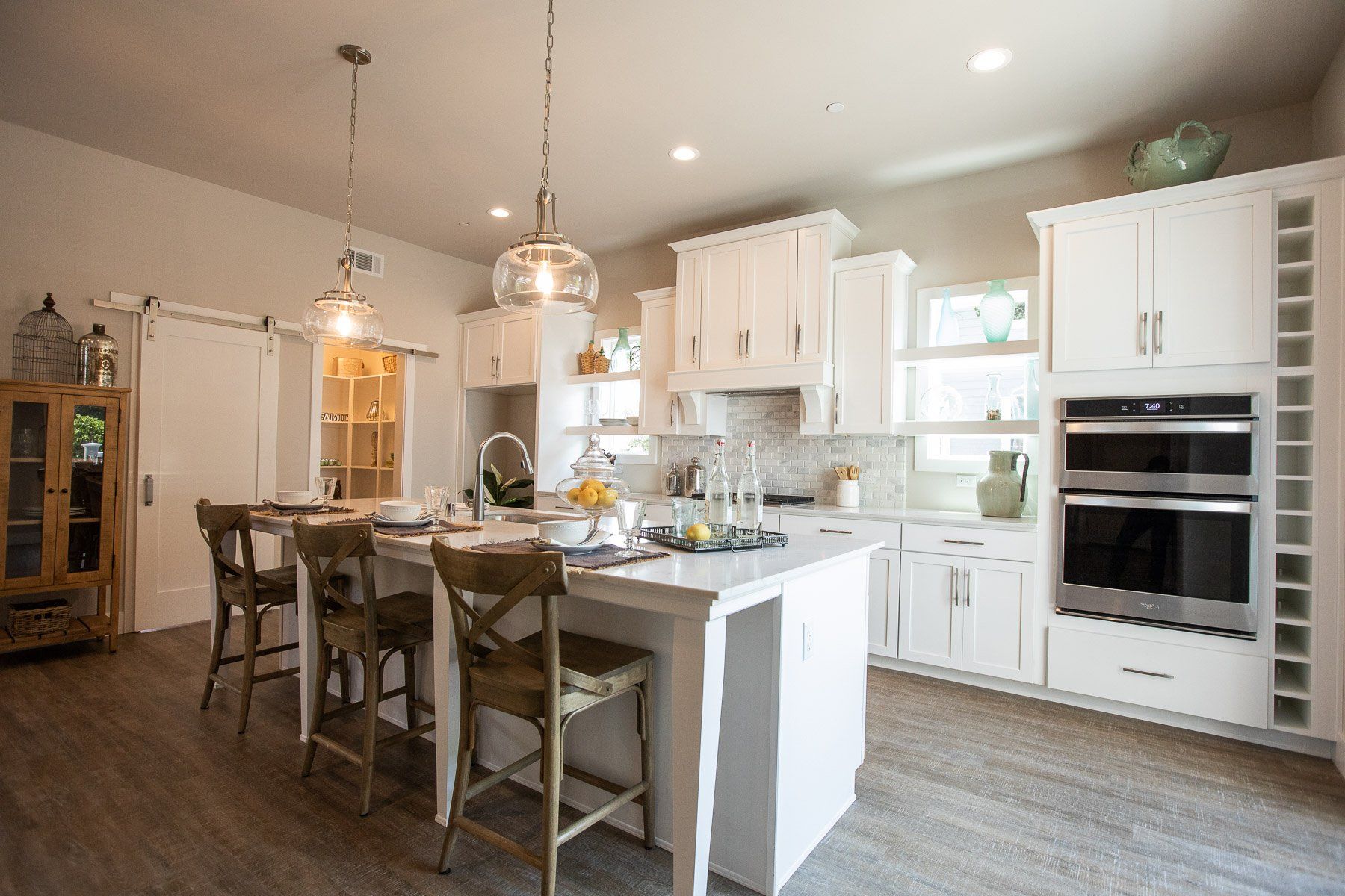 A kitchen with white cabinets , stainless steel appliances , and a large island.