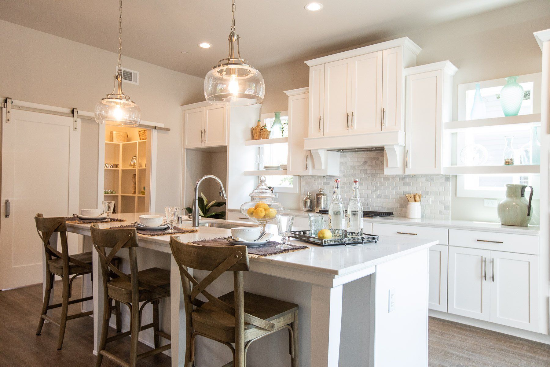A kitchen with white cabinets , a large island , a table and chairs.