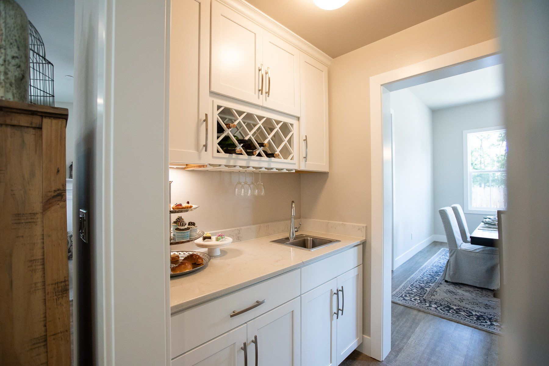 A kitchen with white cabinets , a sink , and a wine rack.
