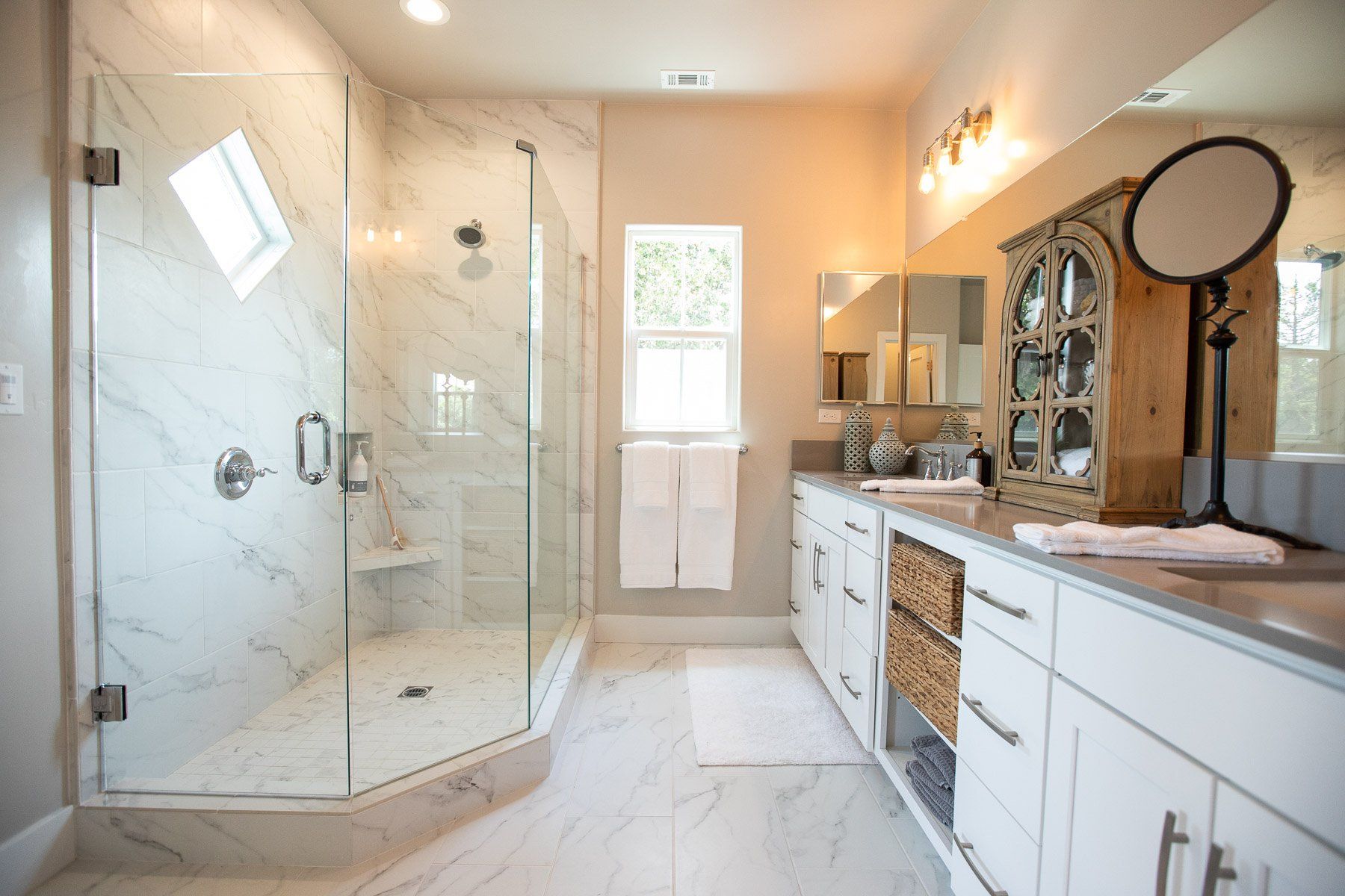 A bathroom with a walk in shower and two sinks.