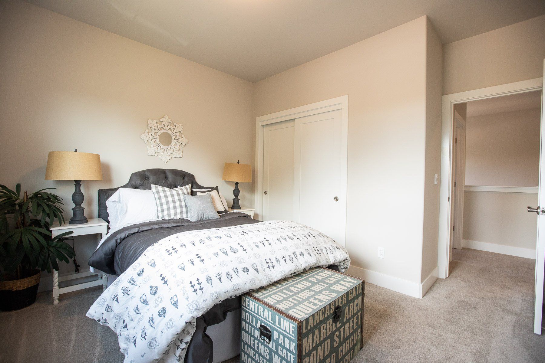 A bedroom with a bed , trunk , lamps and a walk in closet.