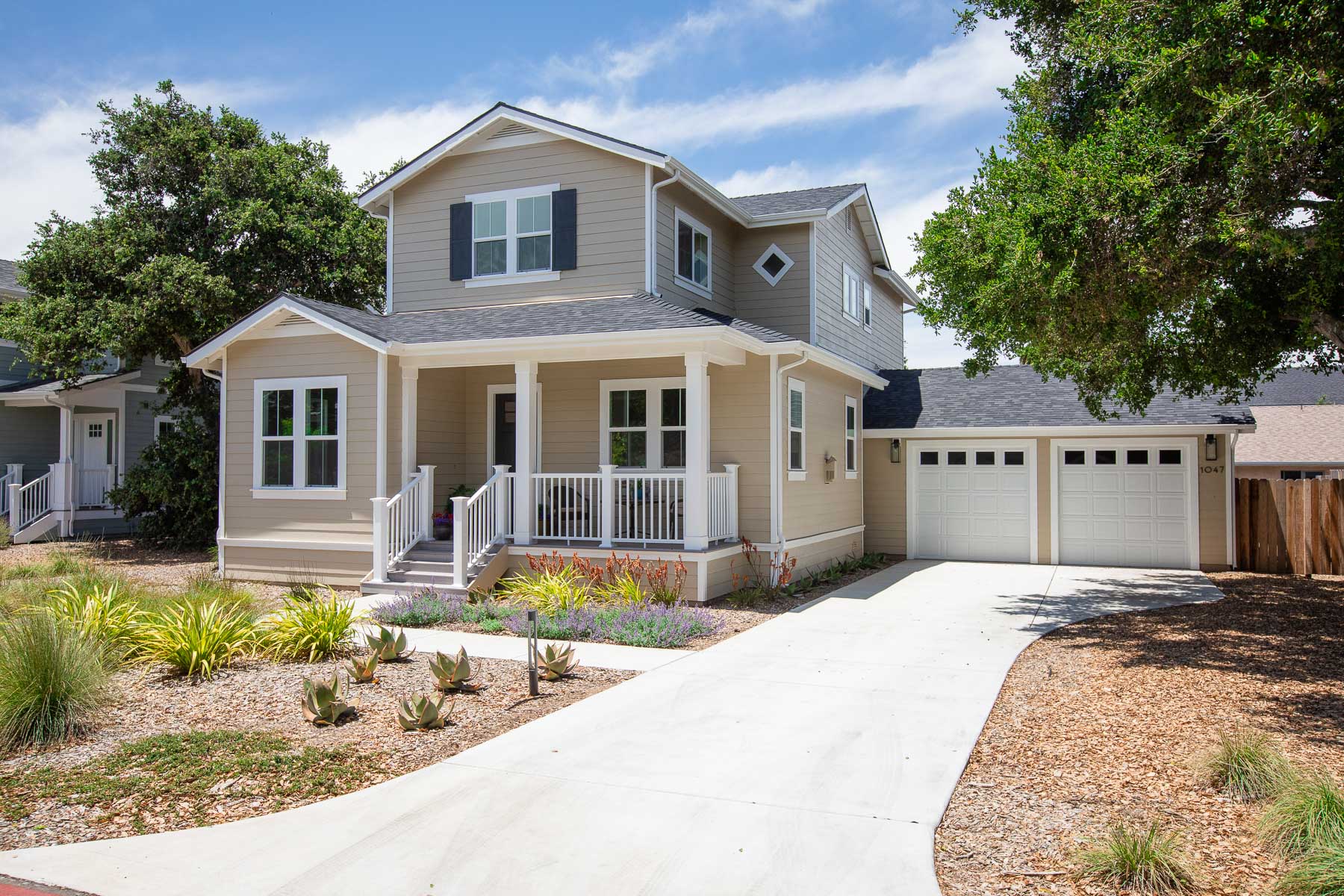 A house with two garages and a porch on a sunny day