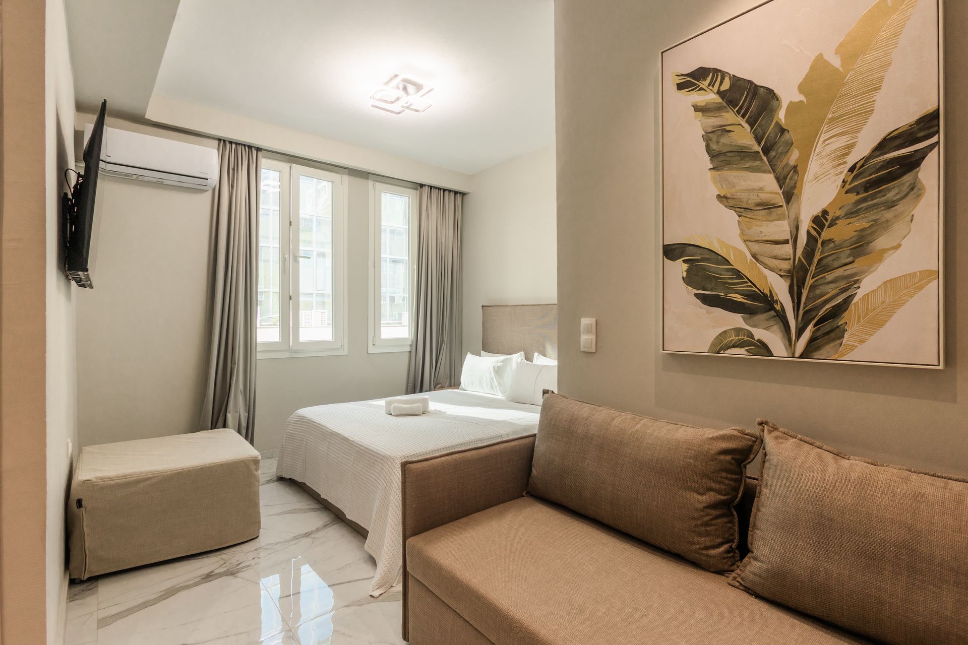 Small hotel room with a bed, couch, and wall art.