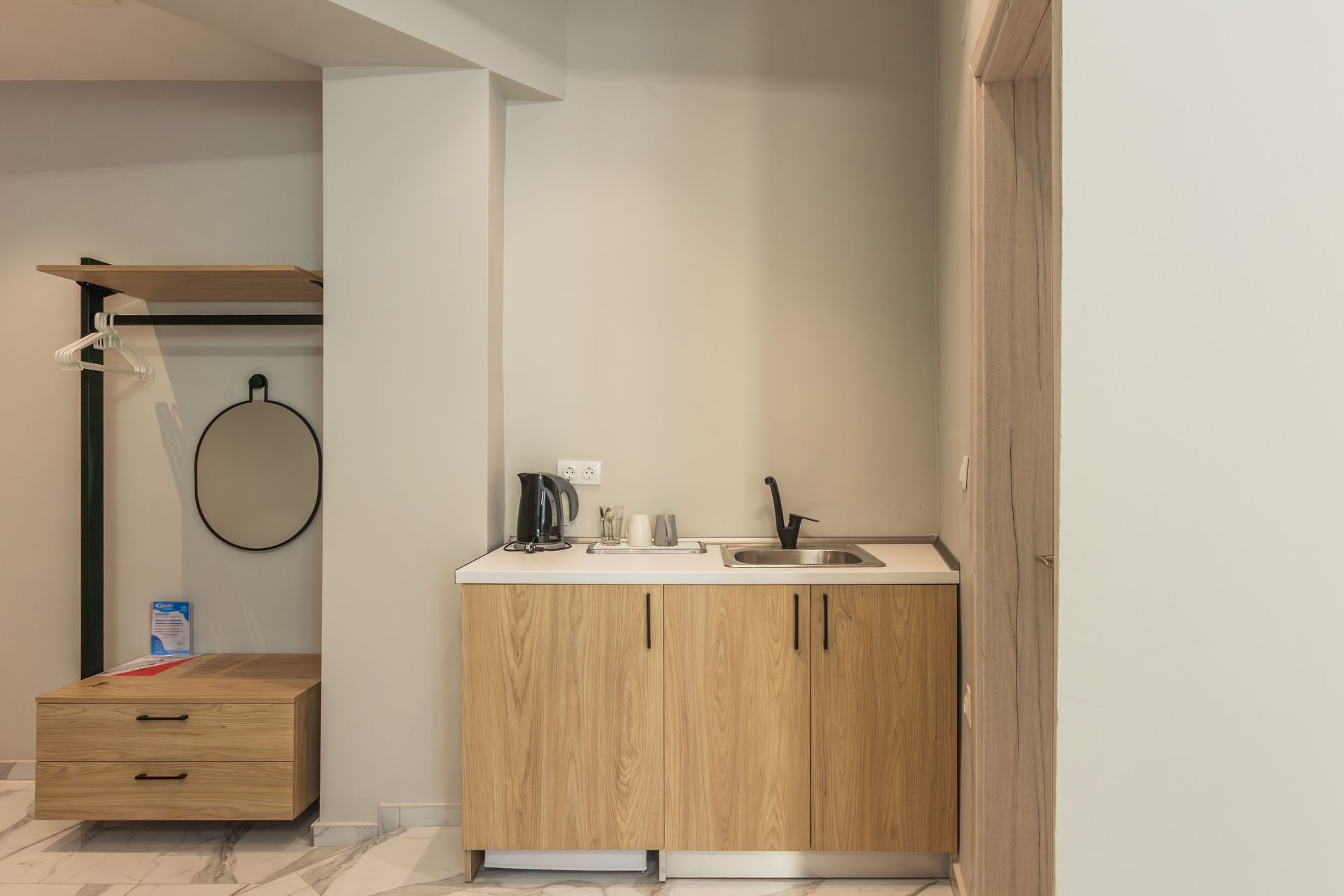 Small hotel room with kitchenette and closet area.