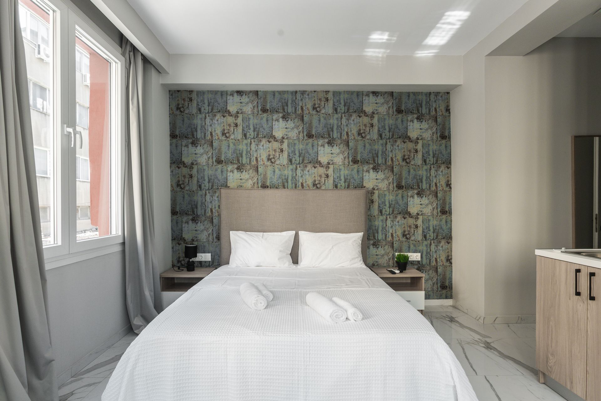 Bedroom with a double bed, gray curtains, and patterned accent wall.
