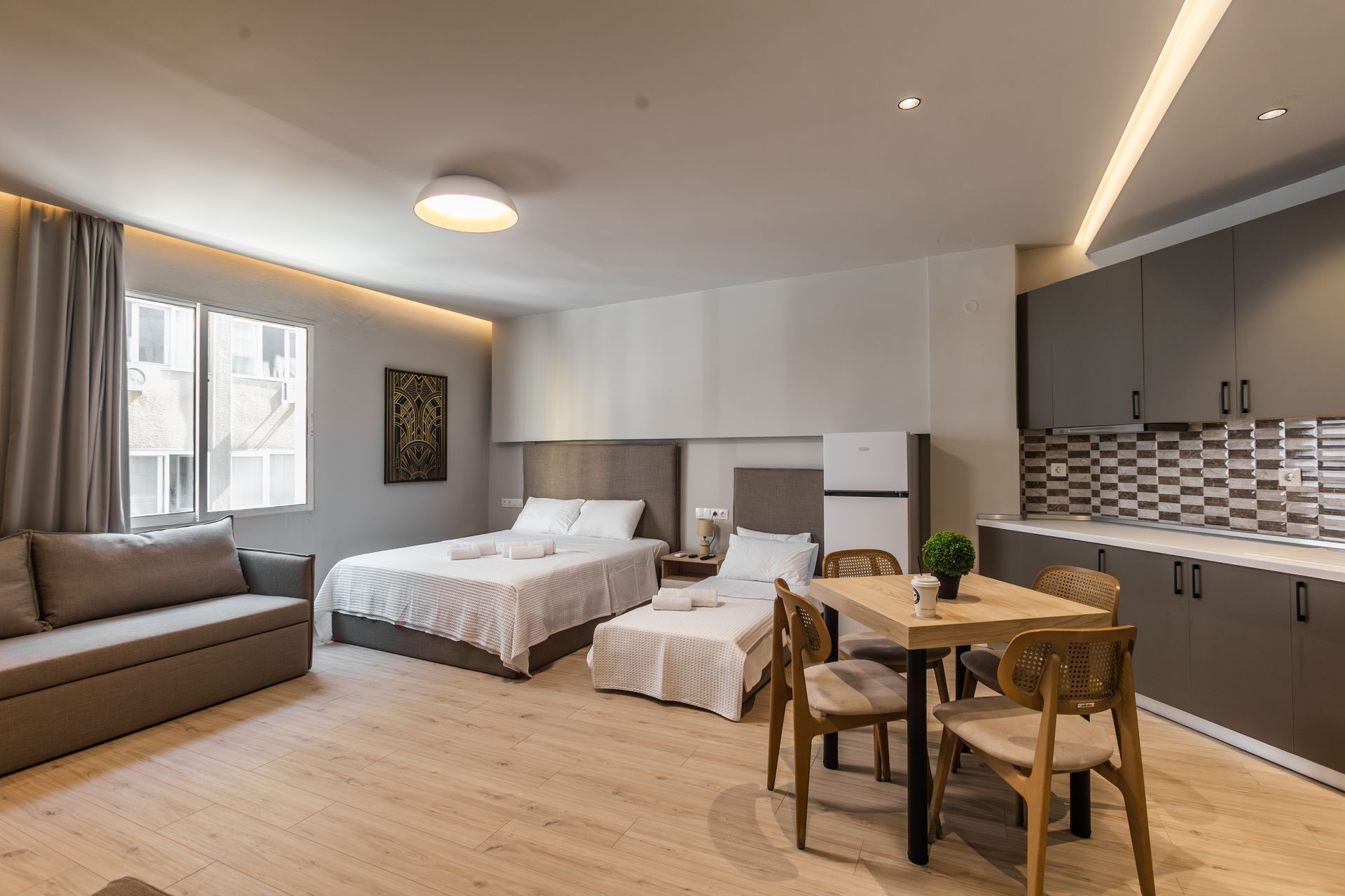 Studio apartment with two beds, a sofa, kitchen, and dining table.