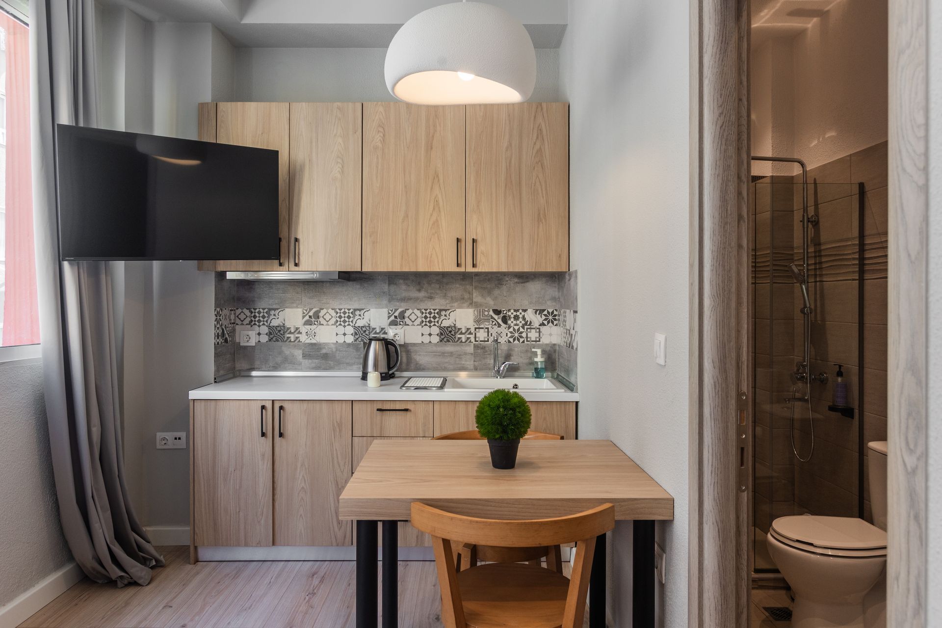 Small studio apartment with kitchenette, dining table, and open bathroom.