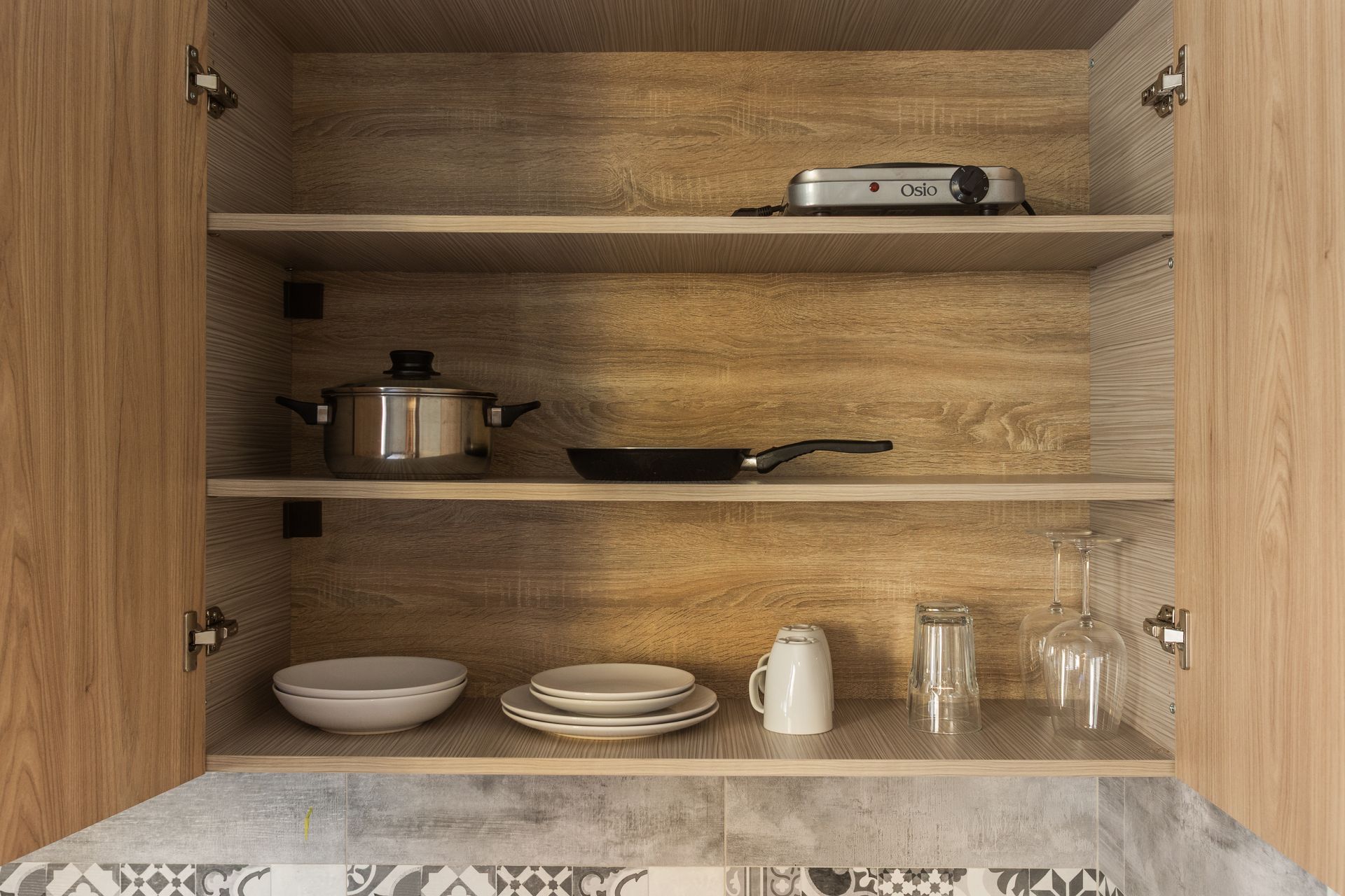 Kitchen cabinet with cookware and dishes on shelves.