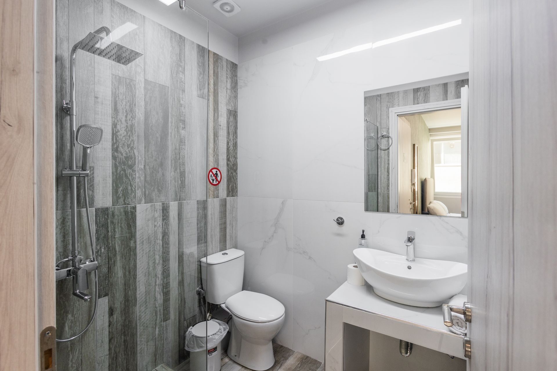 Bathroom with shower, toilet, sink, and mirror. Gray and white color scheme.