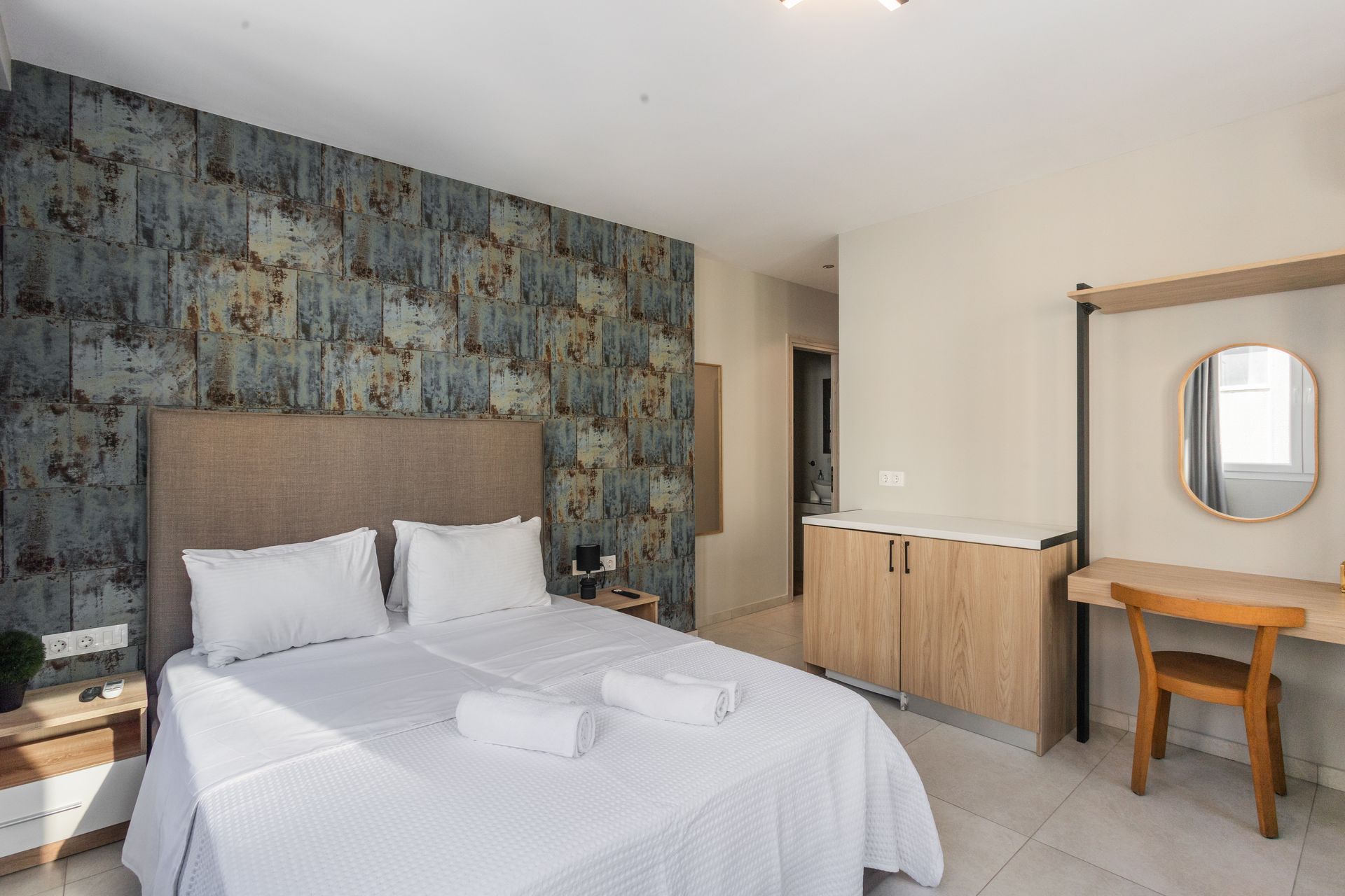 Bedroom with a double bed, rustic accent wall, wooden desk, and cabinet.