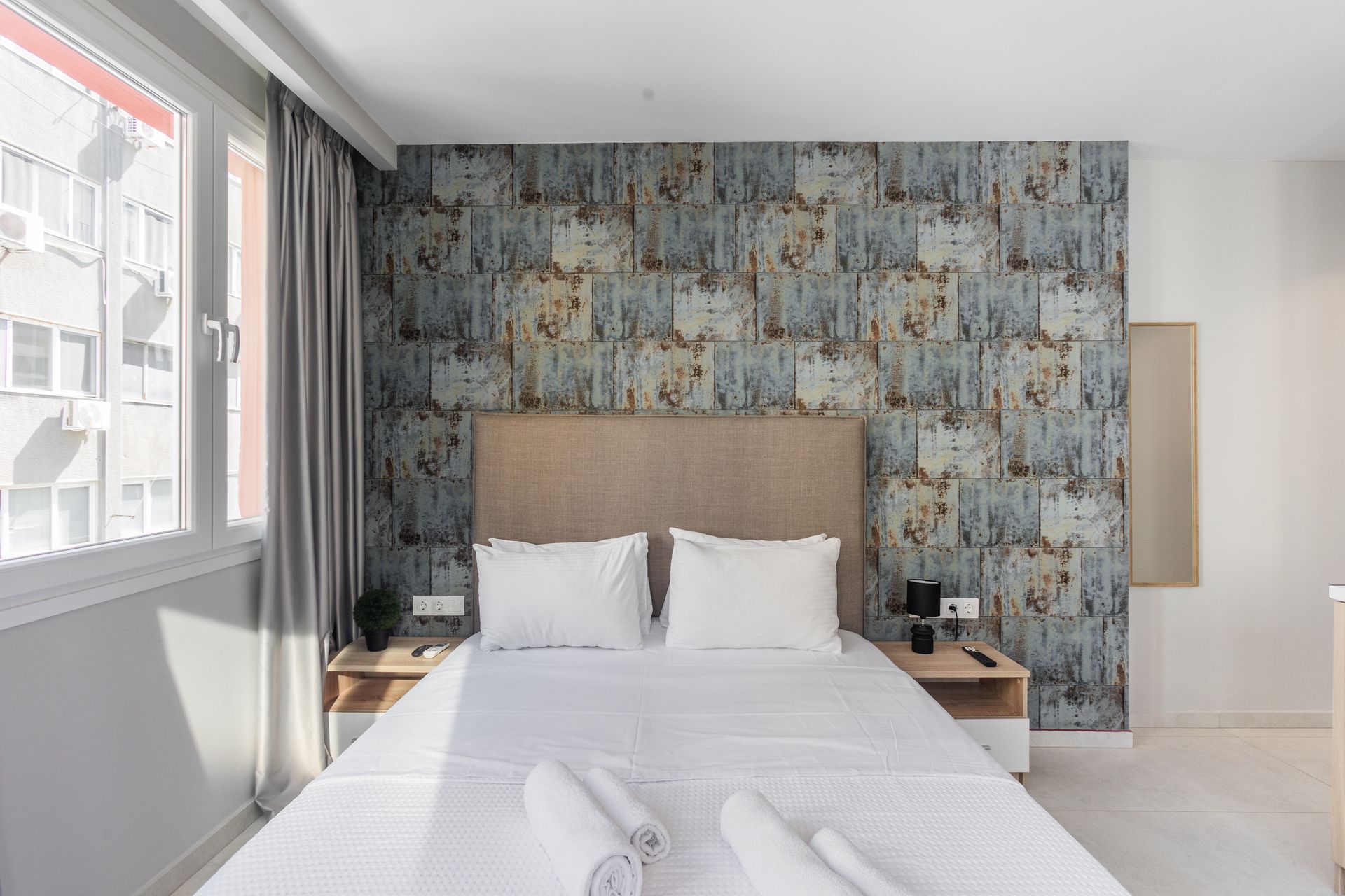 Bedroom with a bed, nightstands, window, and patterned wallpaper.