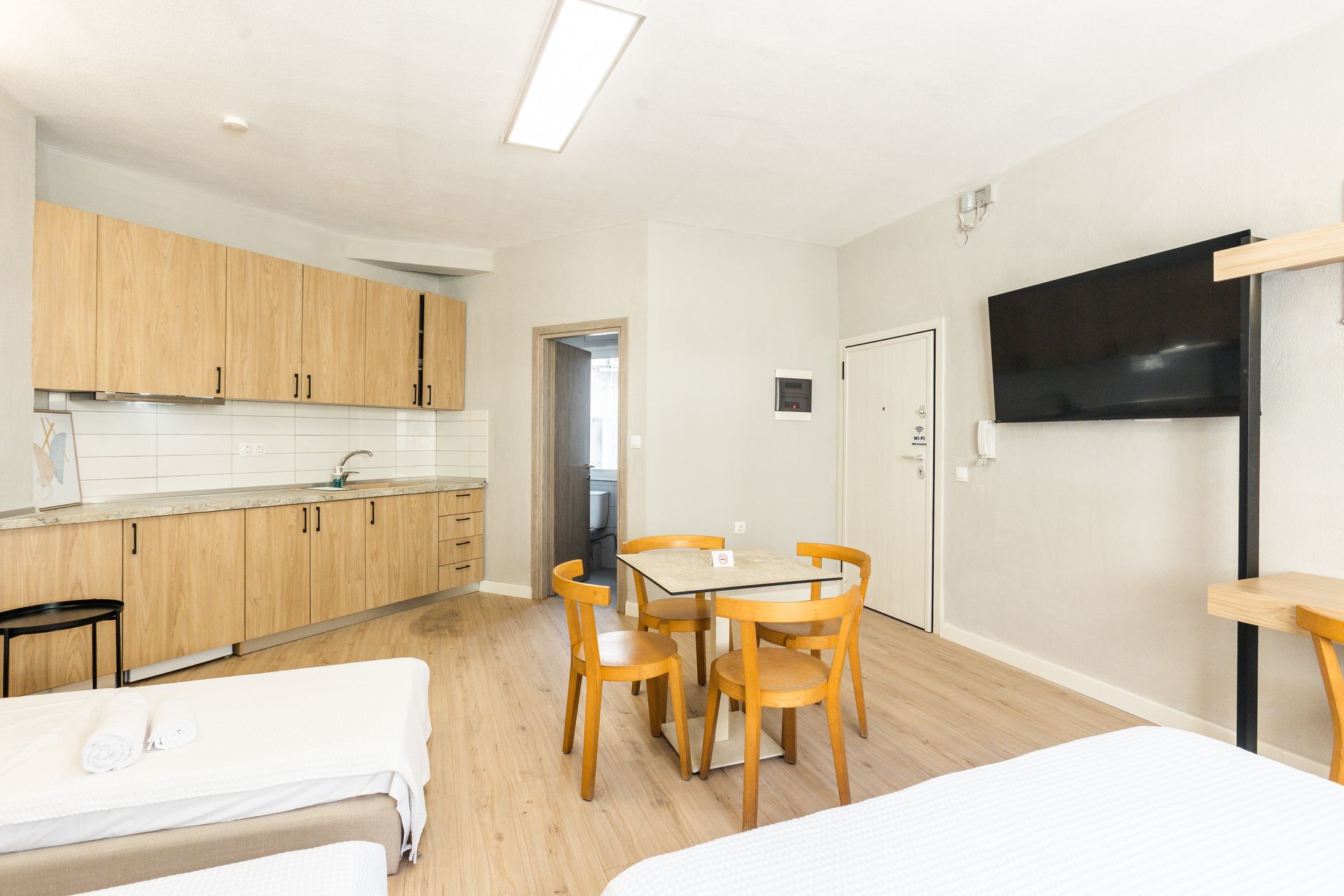 Studio apartment with kitchen, dining area, bed, and mounted TV.