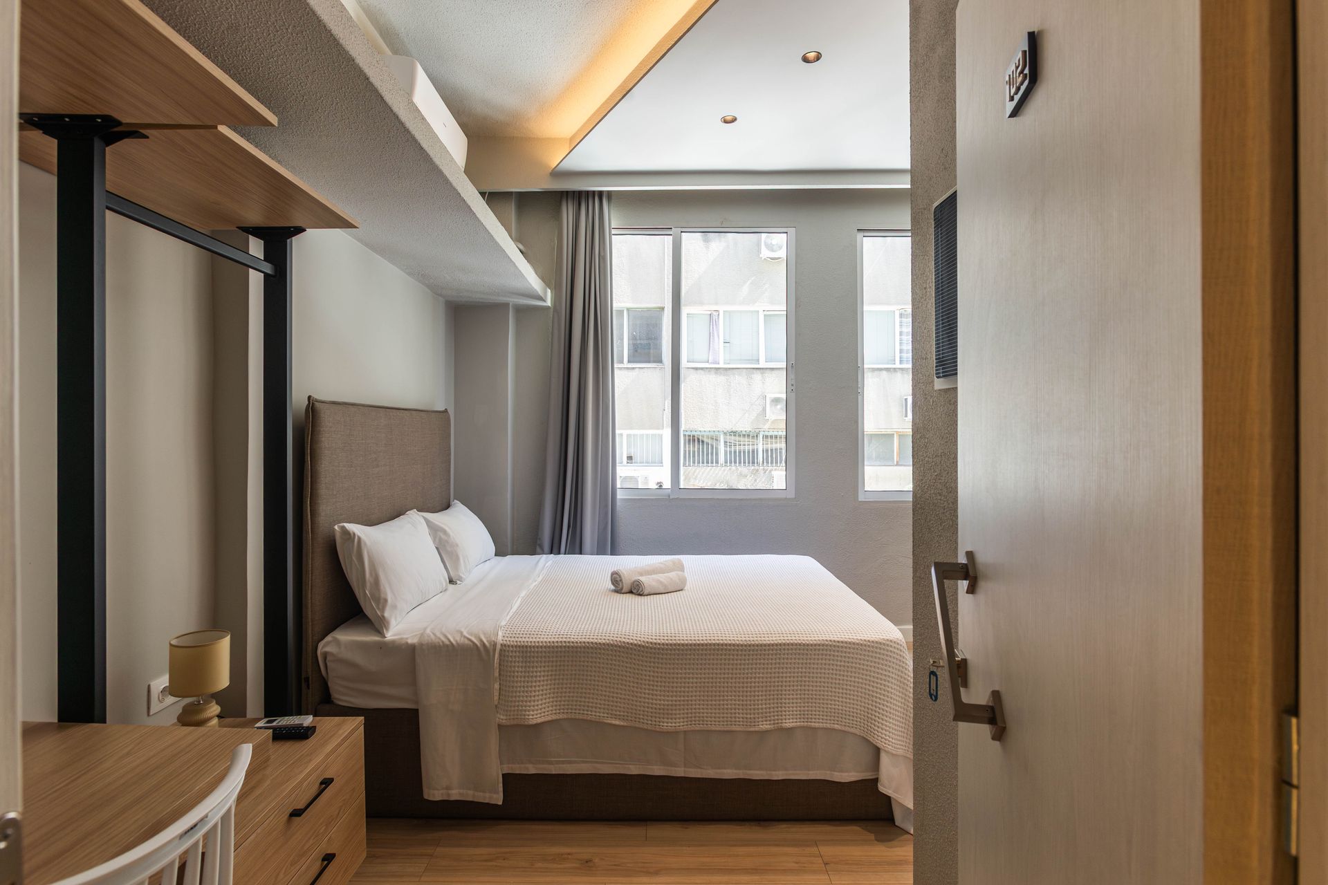 Bedroom with a bed, nightstand, open door, window, and storage shelves.