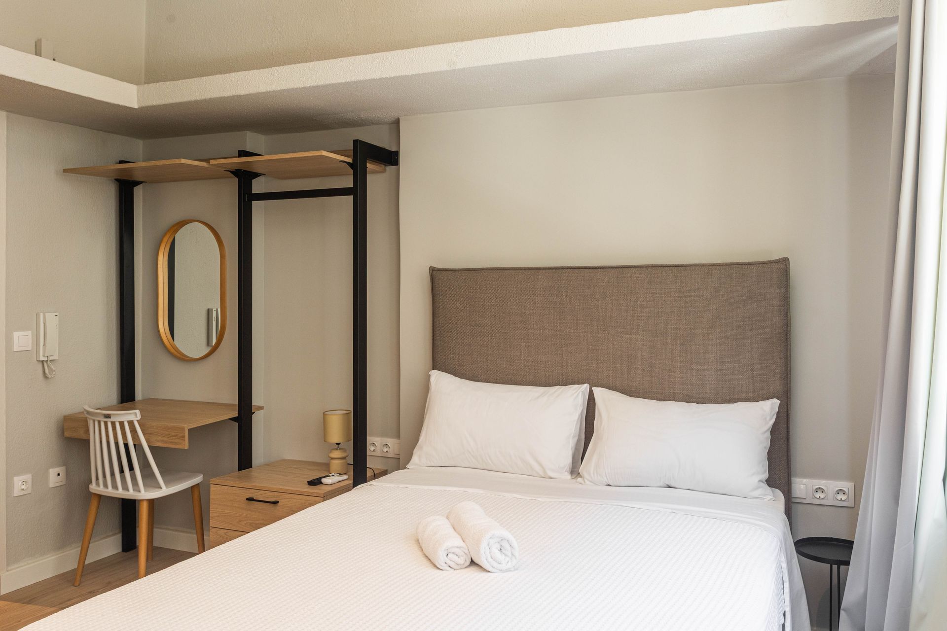 Bedroom with bed, desk, mirror, and open closet. Neutral tones with white bedding.