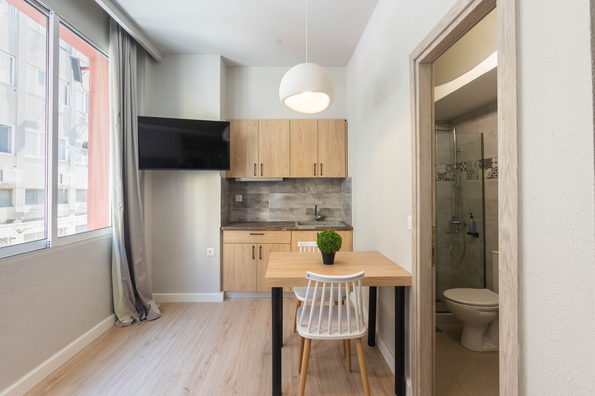 Small apartment interior with kitchen, dining area, and open bathroom.