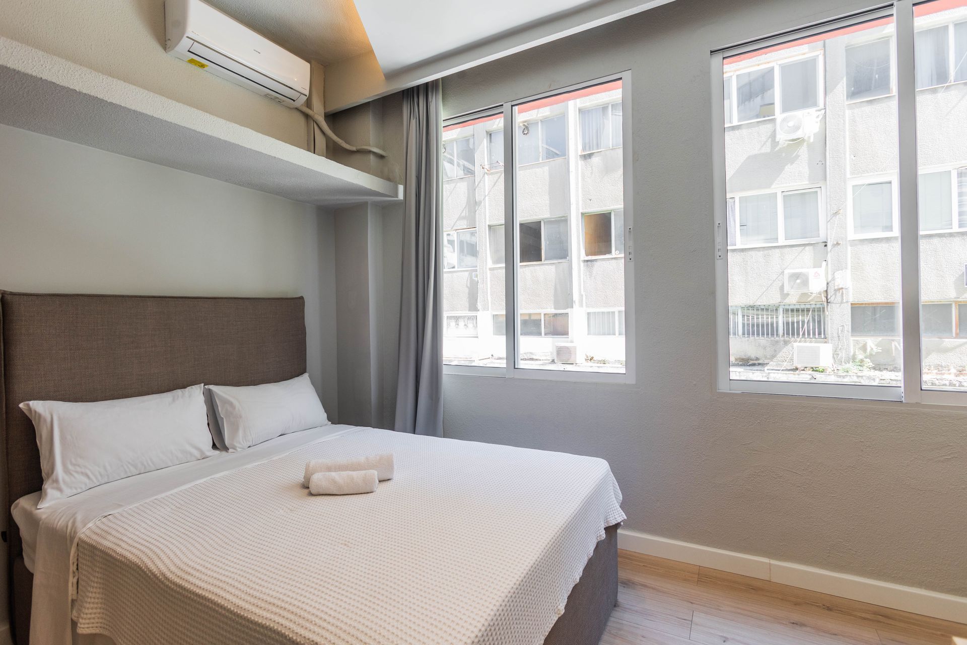 Bedroom with a bed, two windows, and an air conditioner.