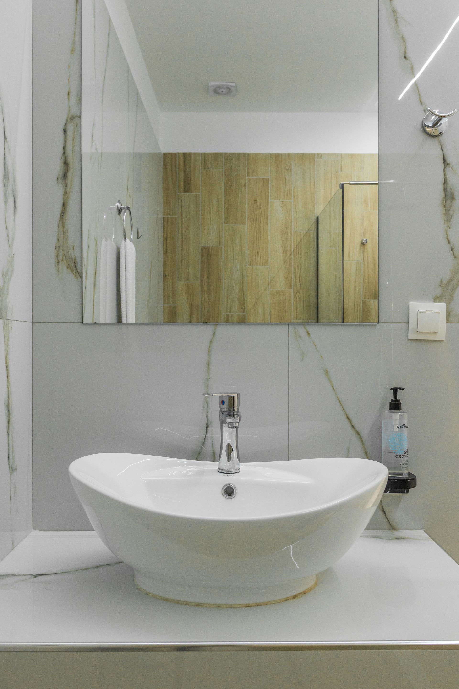 White sink on marble counter in a bathroom with a mirror.