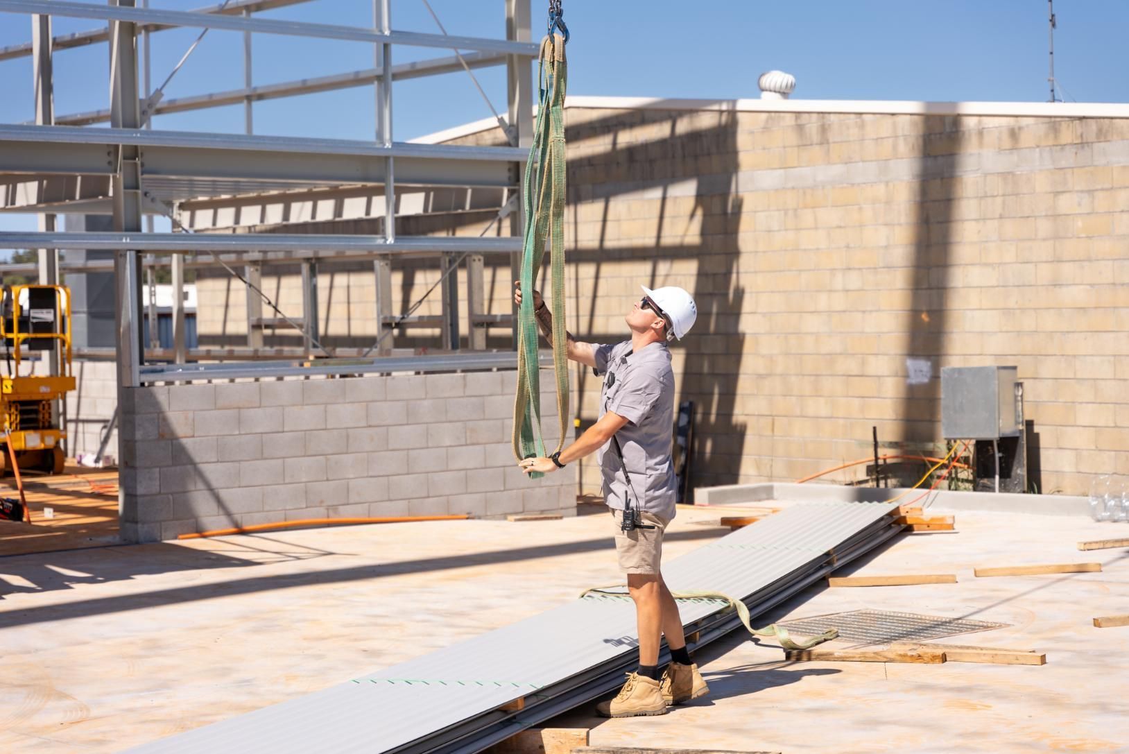 A Construction Worker is Lifting a Metal Structure With a Crane — Roofing Contractor in Laurieton, NSW