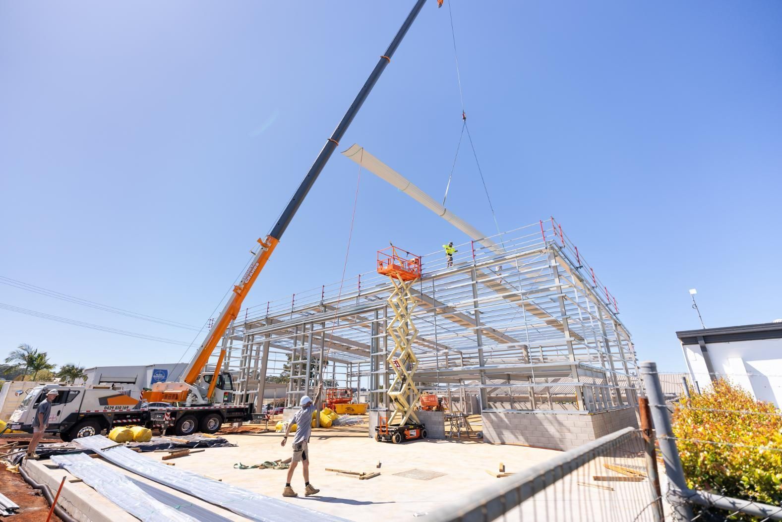 A Construction Site With a Crane Lifting a Metal Structure — Roofing Contractor in Wauchope, NSW