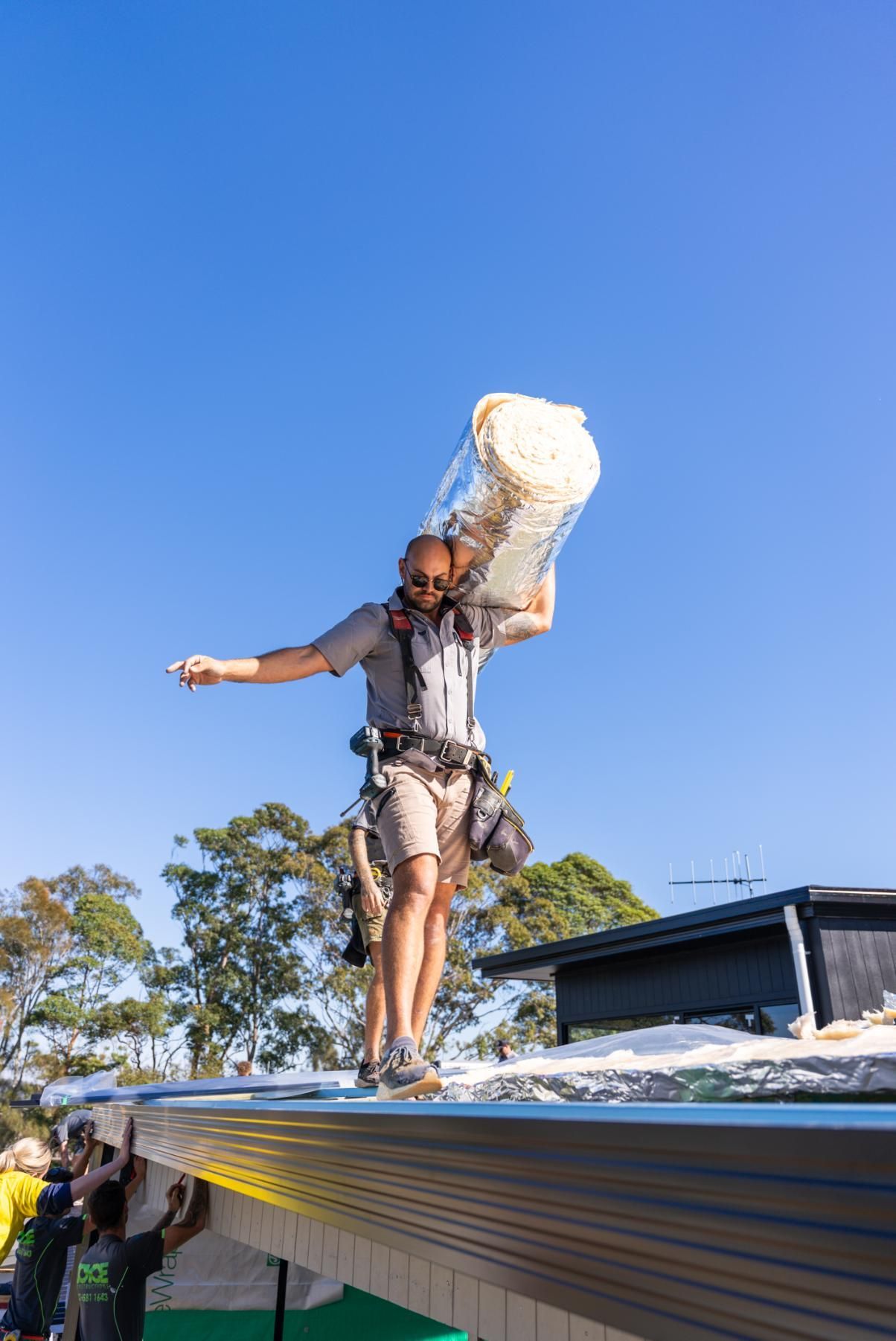 A Construction Site With A Crane and a Man Standing in Front Of It — Roofing Contractor in Wauchope, NSW