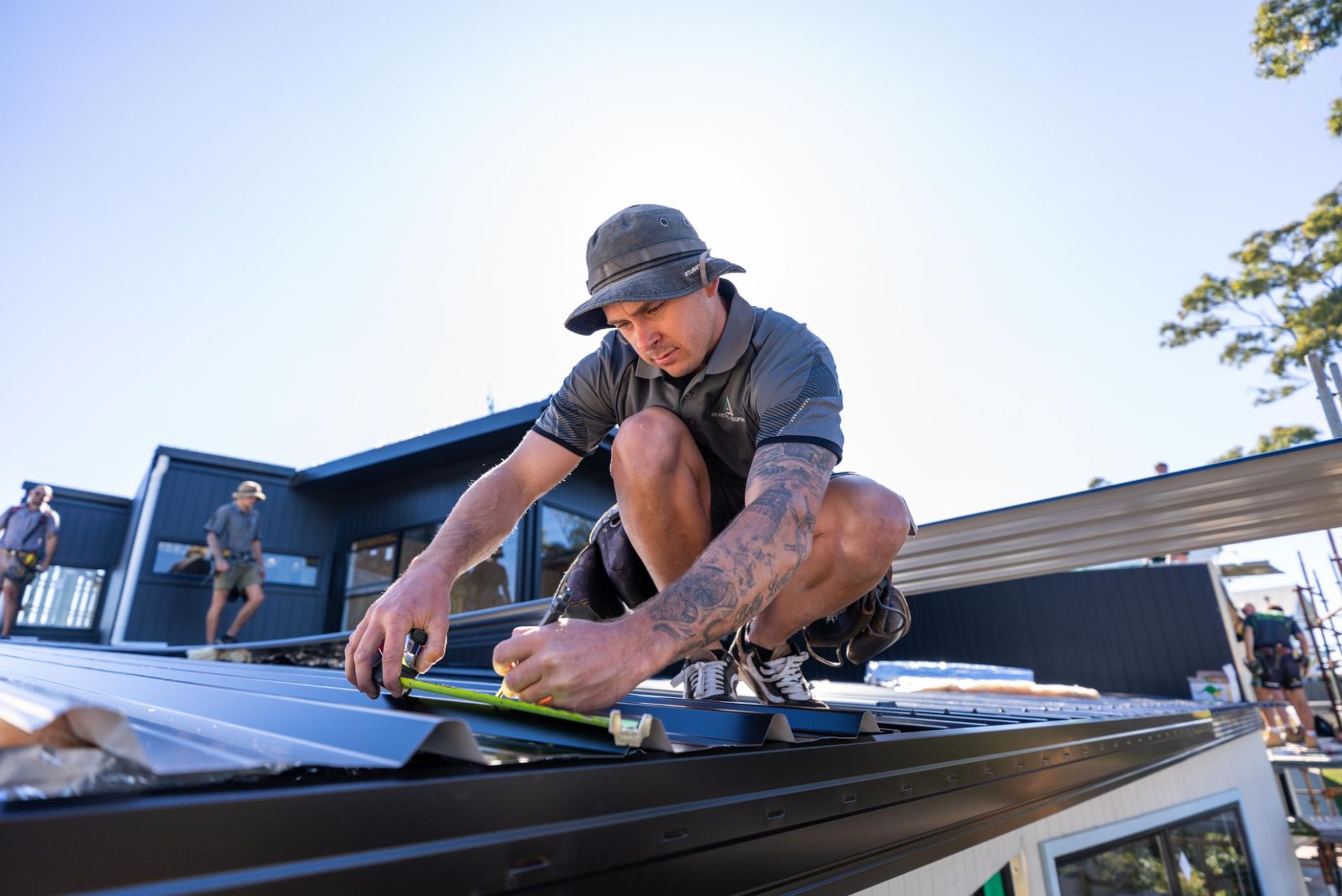 A Man Is Kneeling on Top of a Roof Measuring a Piece of Metal — Roofing Contractor in Wauchope, NSW