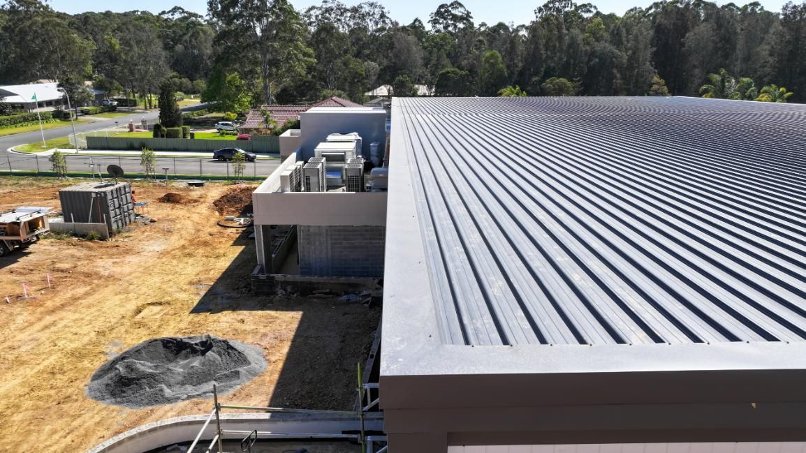 An Aerial View of a Building Under Construction With a Black Roof — Roofing Contractor in Wauchope, NSW