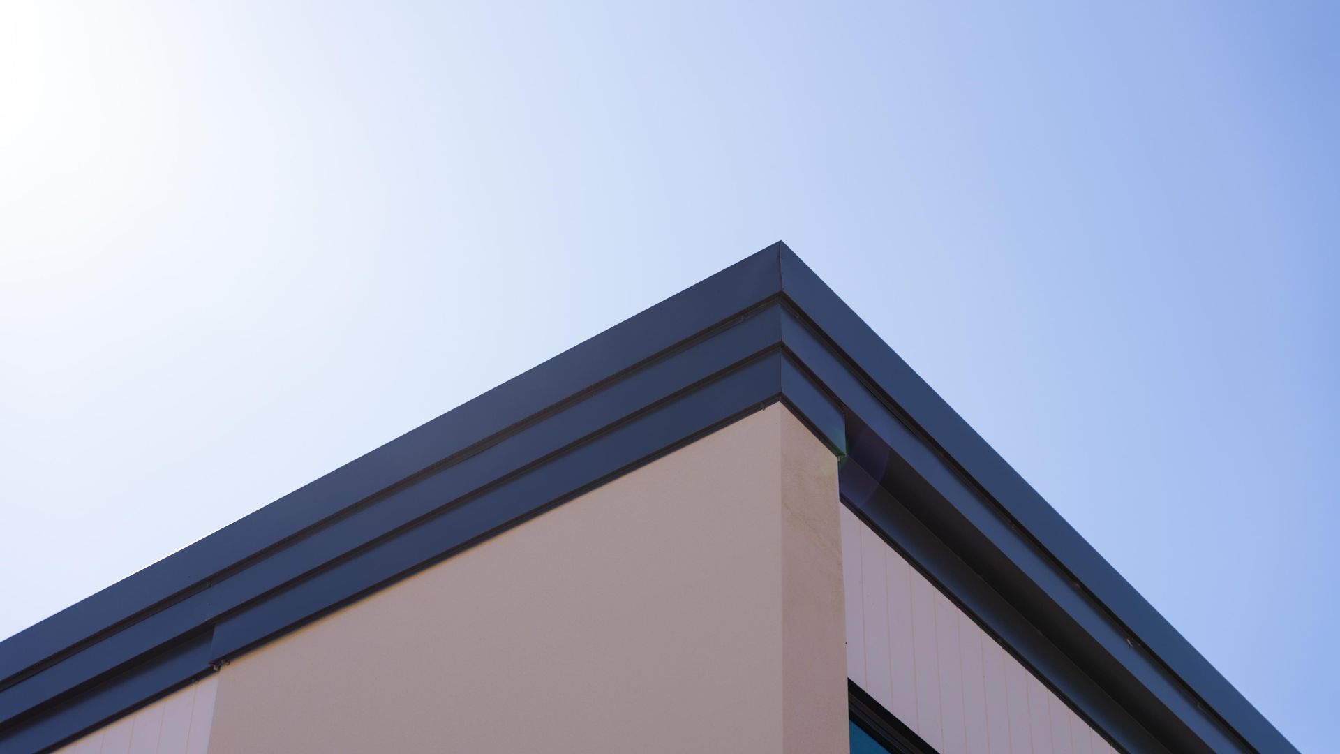 Looking Up at the Corner of a Building with a Blue Sky in the Background — Roofing Contractor in Forster, NSW
