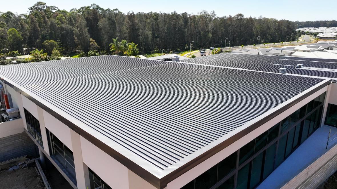A Building With Solar Panel On The Roof — Roofing Contractor in Forster, NSW
