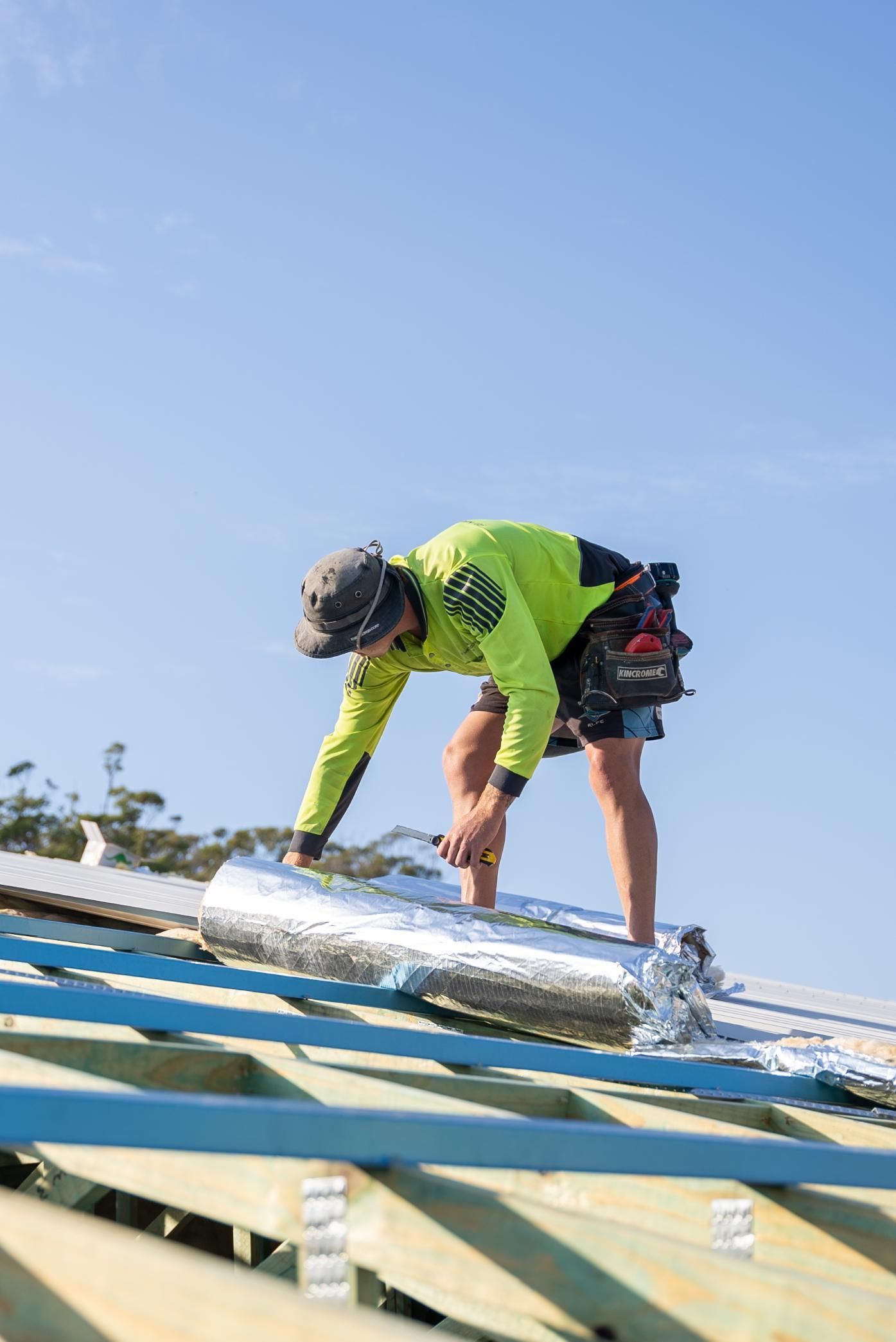 A Construction Site With a Crane Lifting a Building — Roofing Contractor in Wauchope, NSW