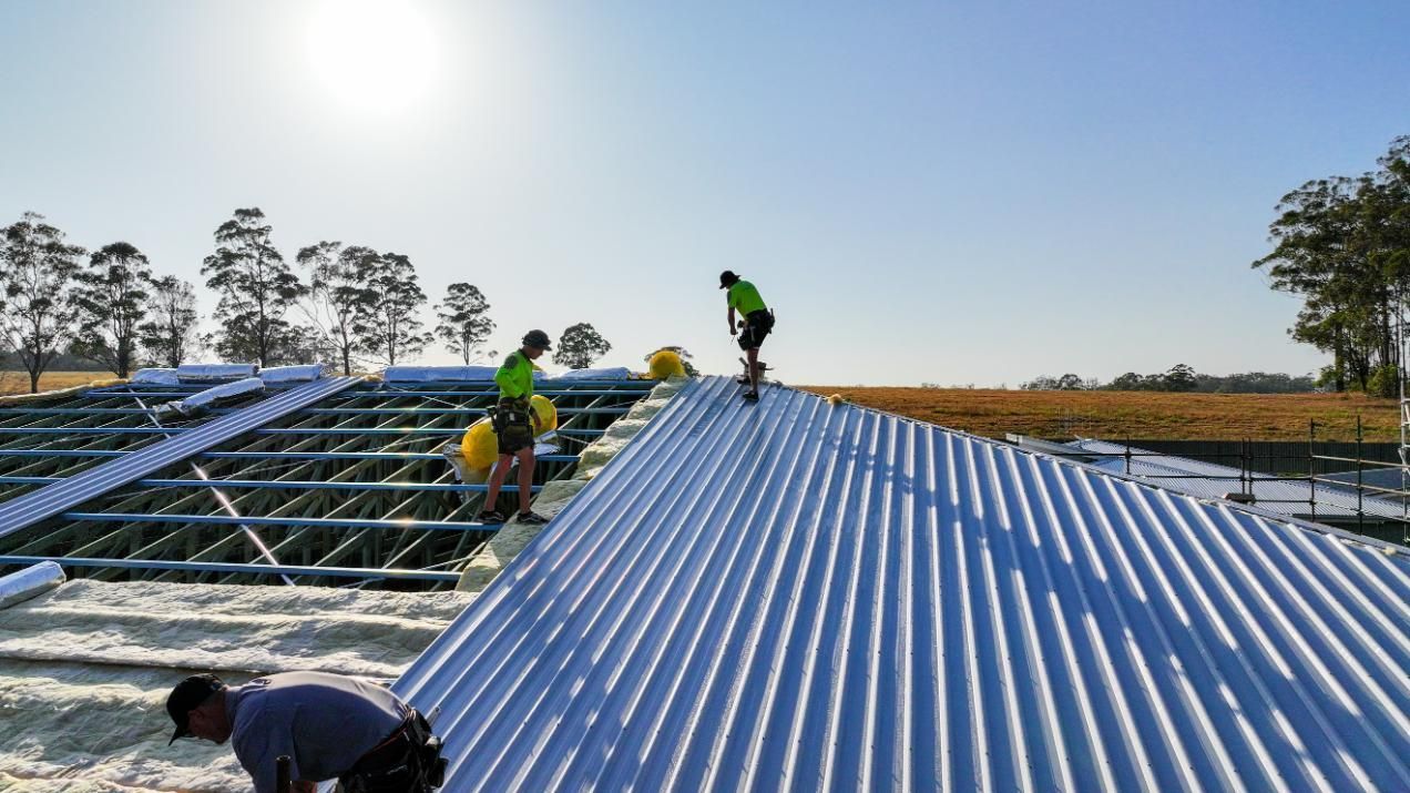 A Construction Worker is Lifting a Metal Structure with a Crane — Roofing Contractor in Wauchope, NSW
