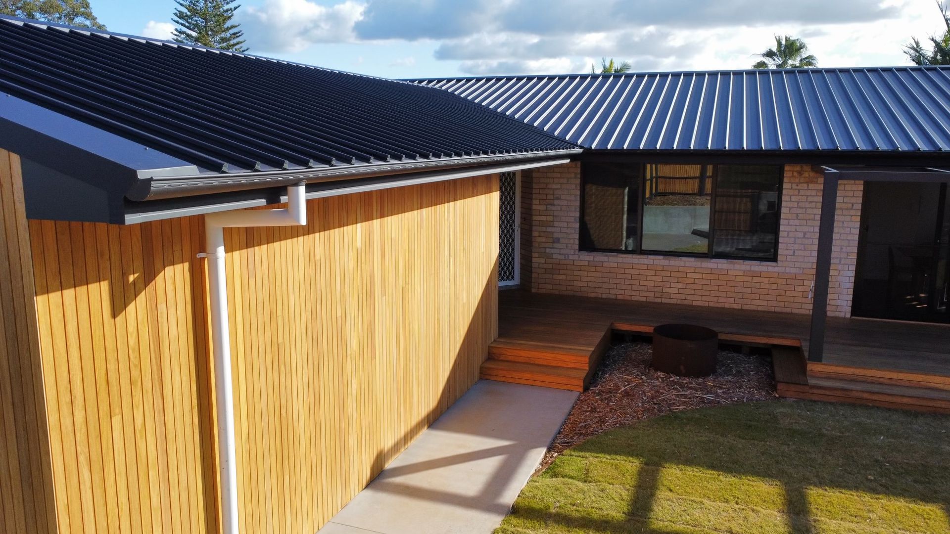 A Man is Standing on Top of a Roof Holding a Large Piece of Foam — Roofing Contractor in Wauchope, NSW