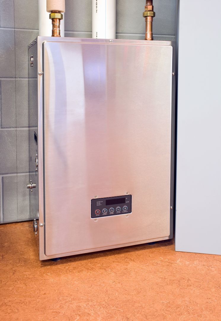 A stainless steel water heater is sitting on a cork floor in a room.