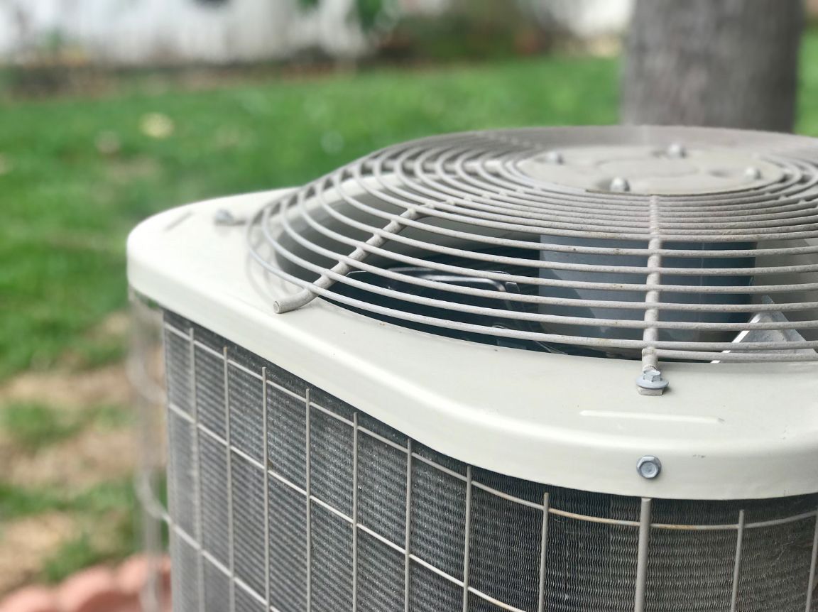 A close up of an air conditioner outside in a yard.