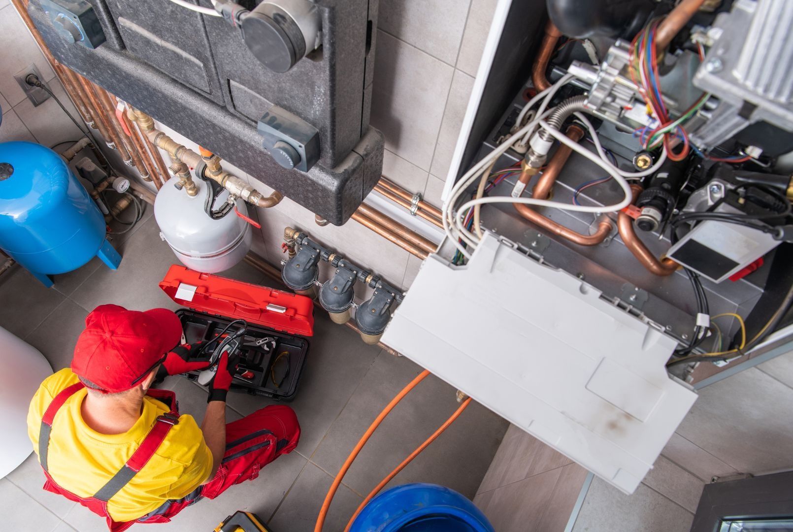 A plumber is working on a boiler in a room.