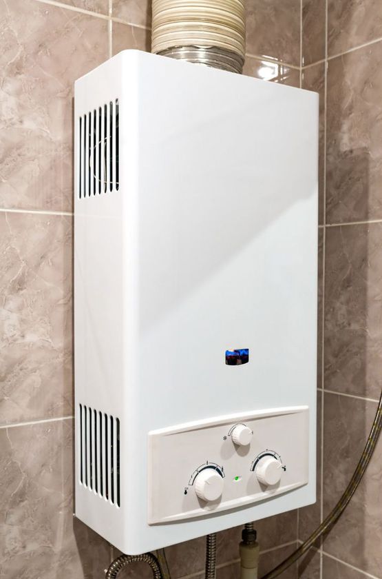 A white gas water heater is hanging on a wall in a bathroom.