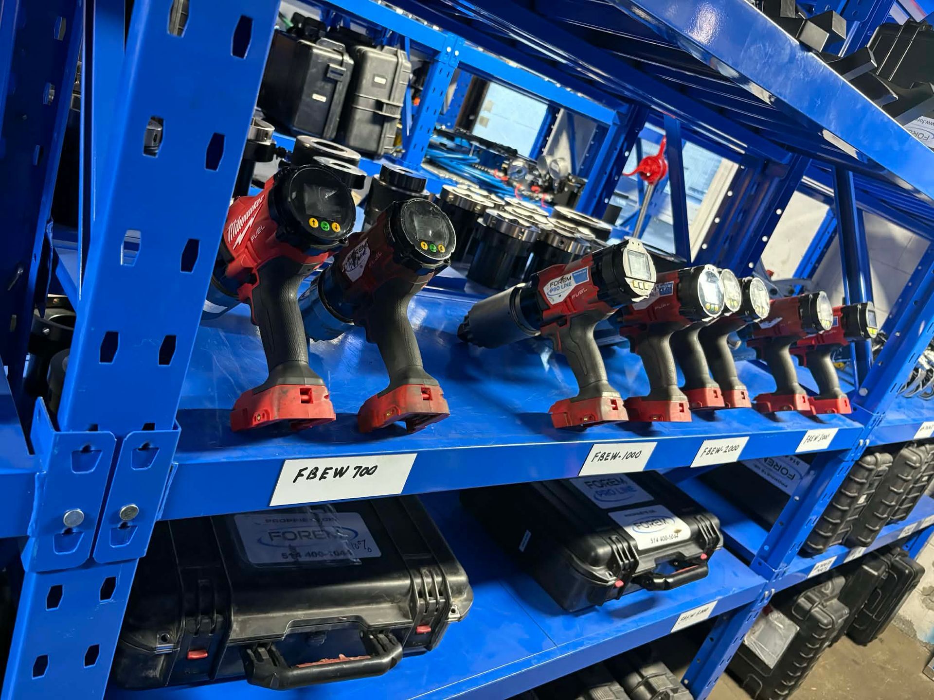 Étagère bleue contenant plusieurs outils électriques rouges et noirs et leurs coffrets noirs.