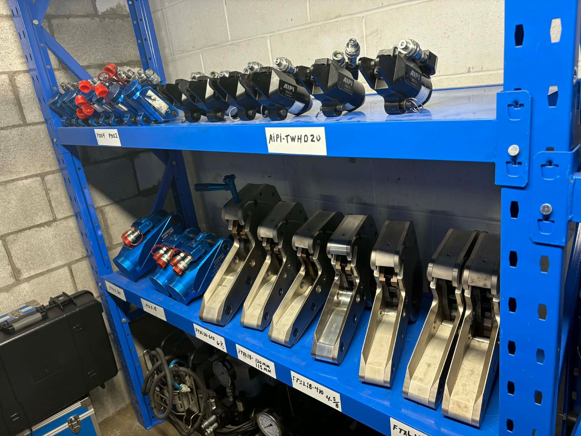 Étagère métallique bleue contenant diverses pièces industrielles ; principalement de couleur bleue, noire et argentée.