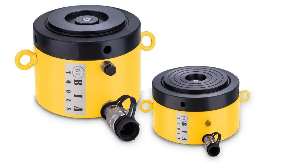 Deux vérins hydrauliques jaunes, un grand, un petit, couvercles et raccords noirs.