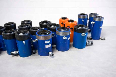 Cylindres hydrauliques bleus et oranges, de tailles diverses, regroupés.