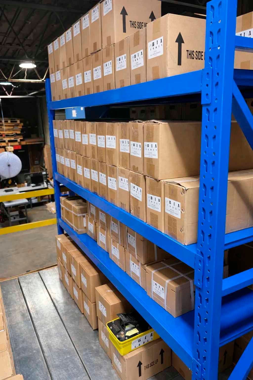 Des étagères métalliques bleues remplies de cartons bruns dans un entrepôt.