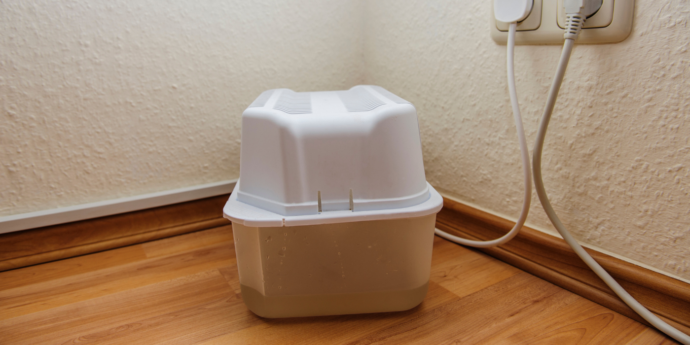 A white humidifier is sitting on a wooden floor next to a wall.