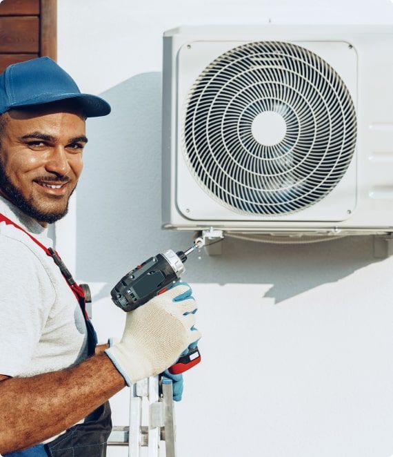 HVAC technician installs an air conditioning unit outside a building, using a drill.