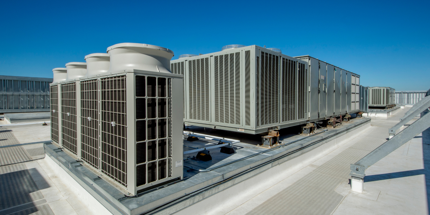 There are a lot of air conditioners on the roof of a building.